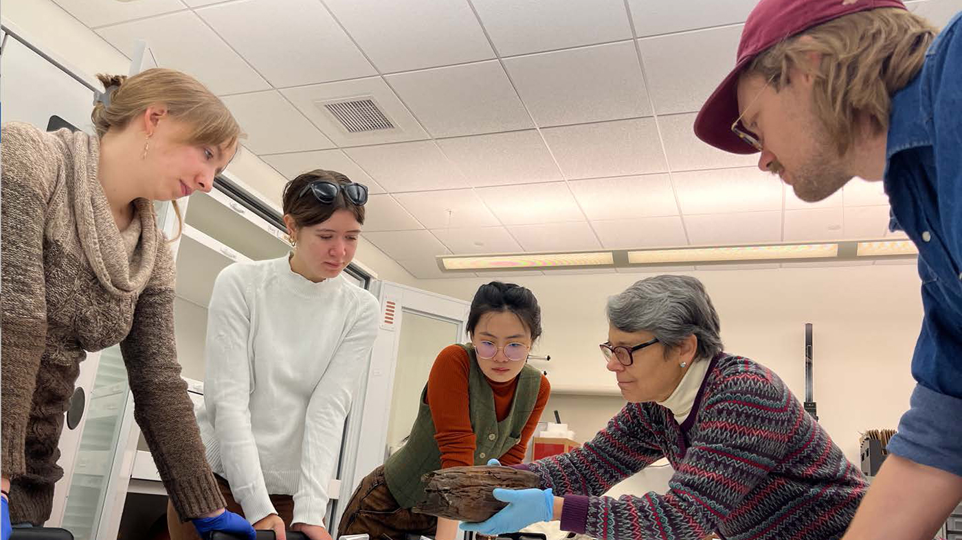 Penn Museum staff examining wooden canoe model