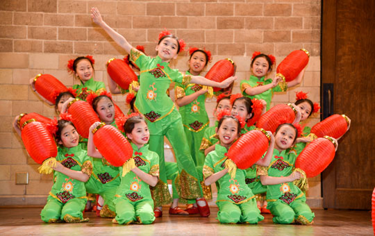 A group of children performing a dance with lanterns.