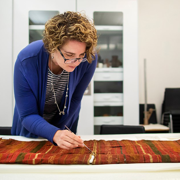 Anne Tiballi working with textiles in the collection.