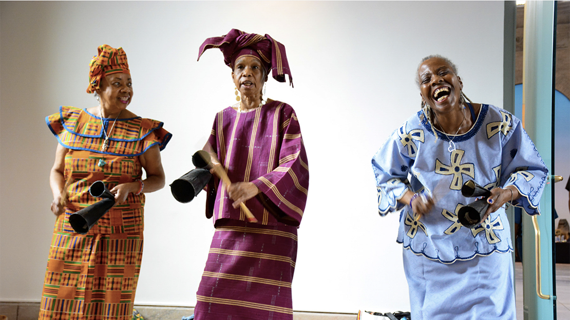 3 women in African garb, dancing
