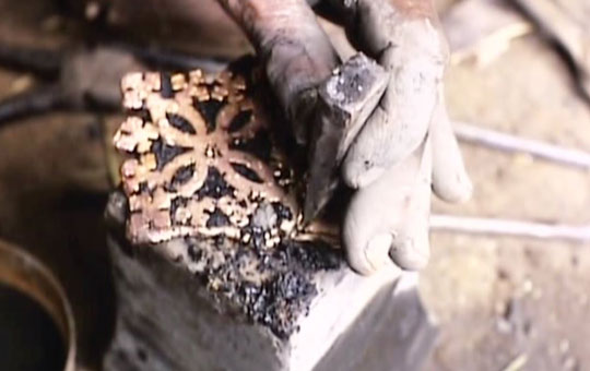 Someone chiseling a silver cast.