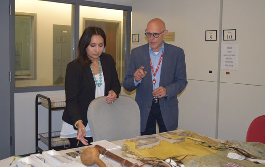 Two individuals examining artifacts in storage