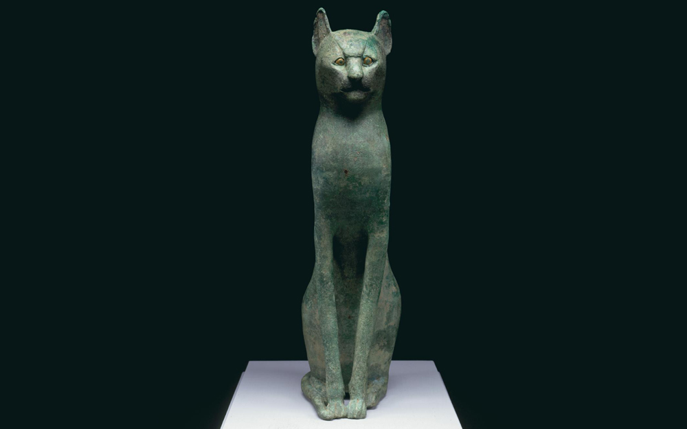Hollow cast bronze statue of a seated cat, with gold leaf applied to eyes.