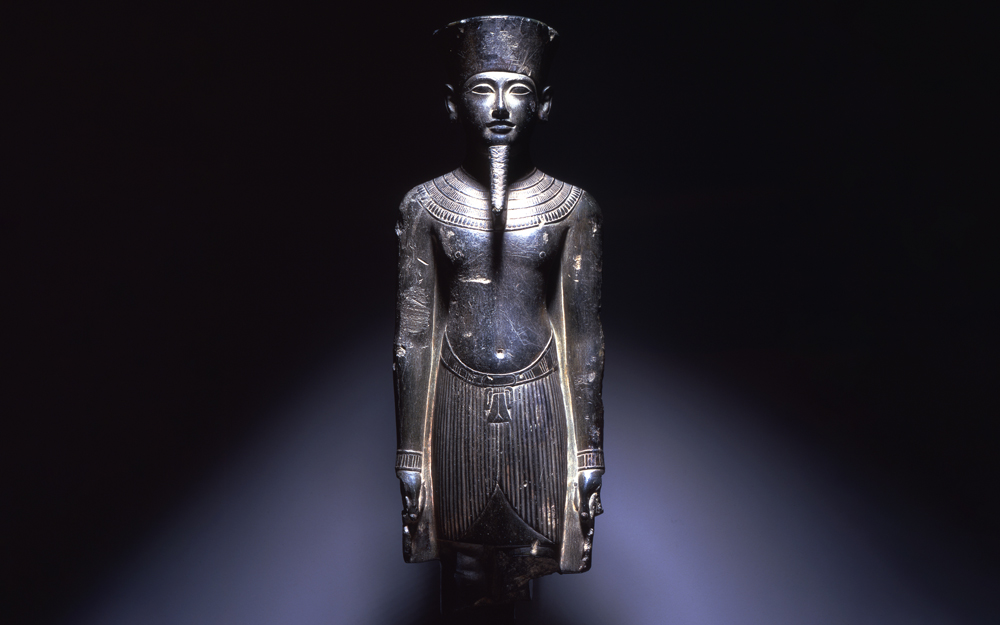 Standing graywacke statue of Amun, preserved from the knees up. 