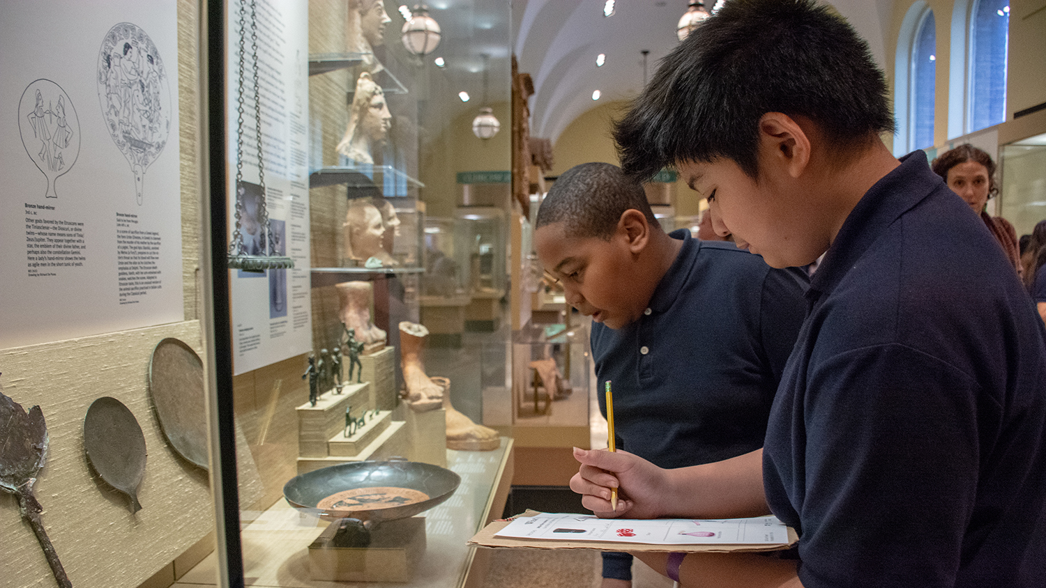School children taking notes while on a museum tour.