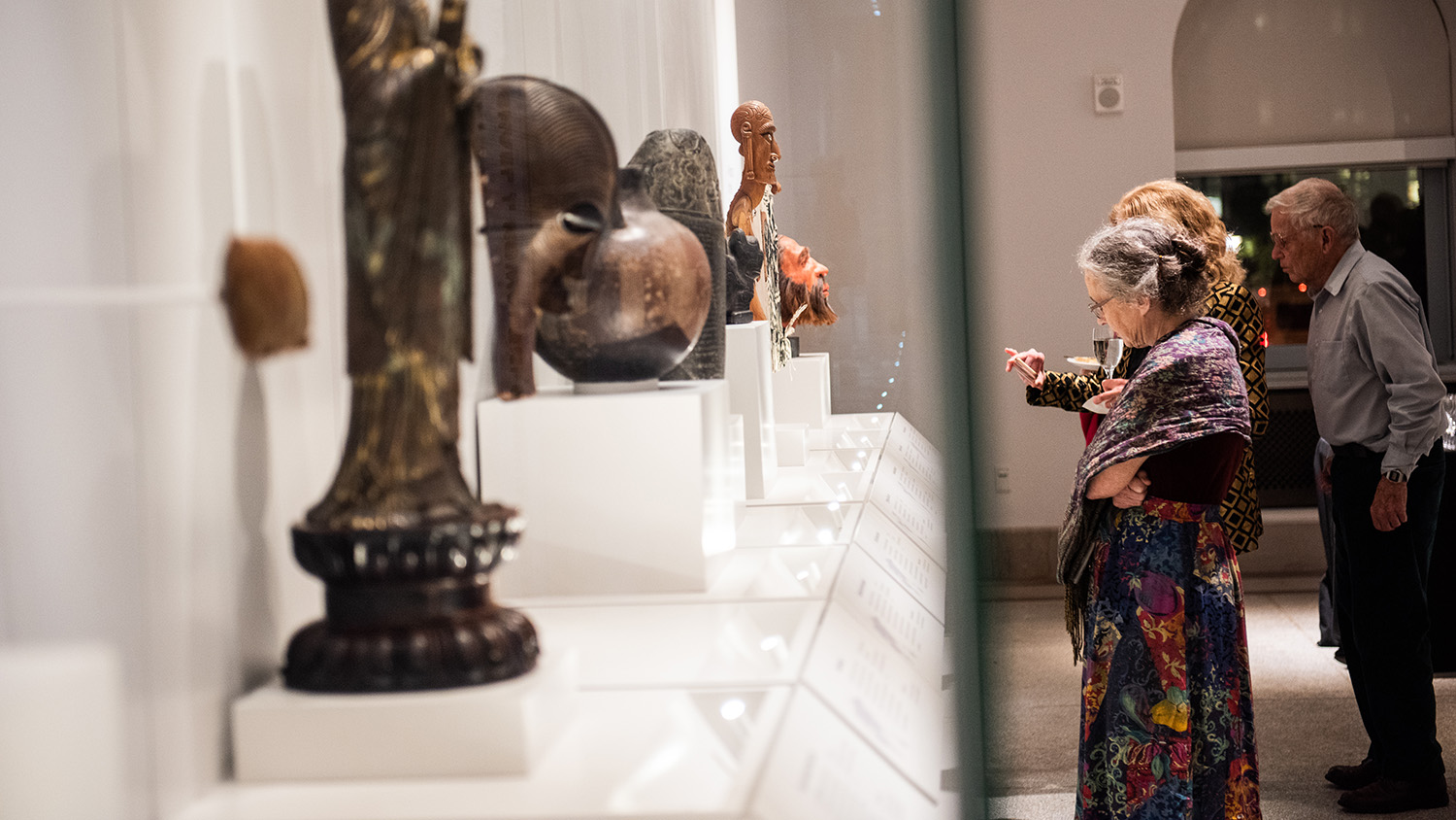 Three visitors looking at objects on display.