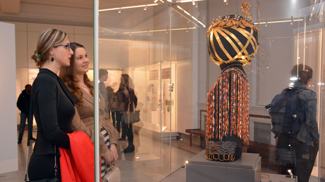 two women looking at queen puabis headdress.