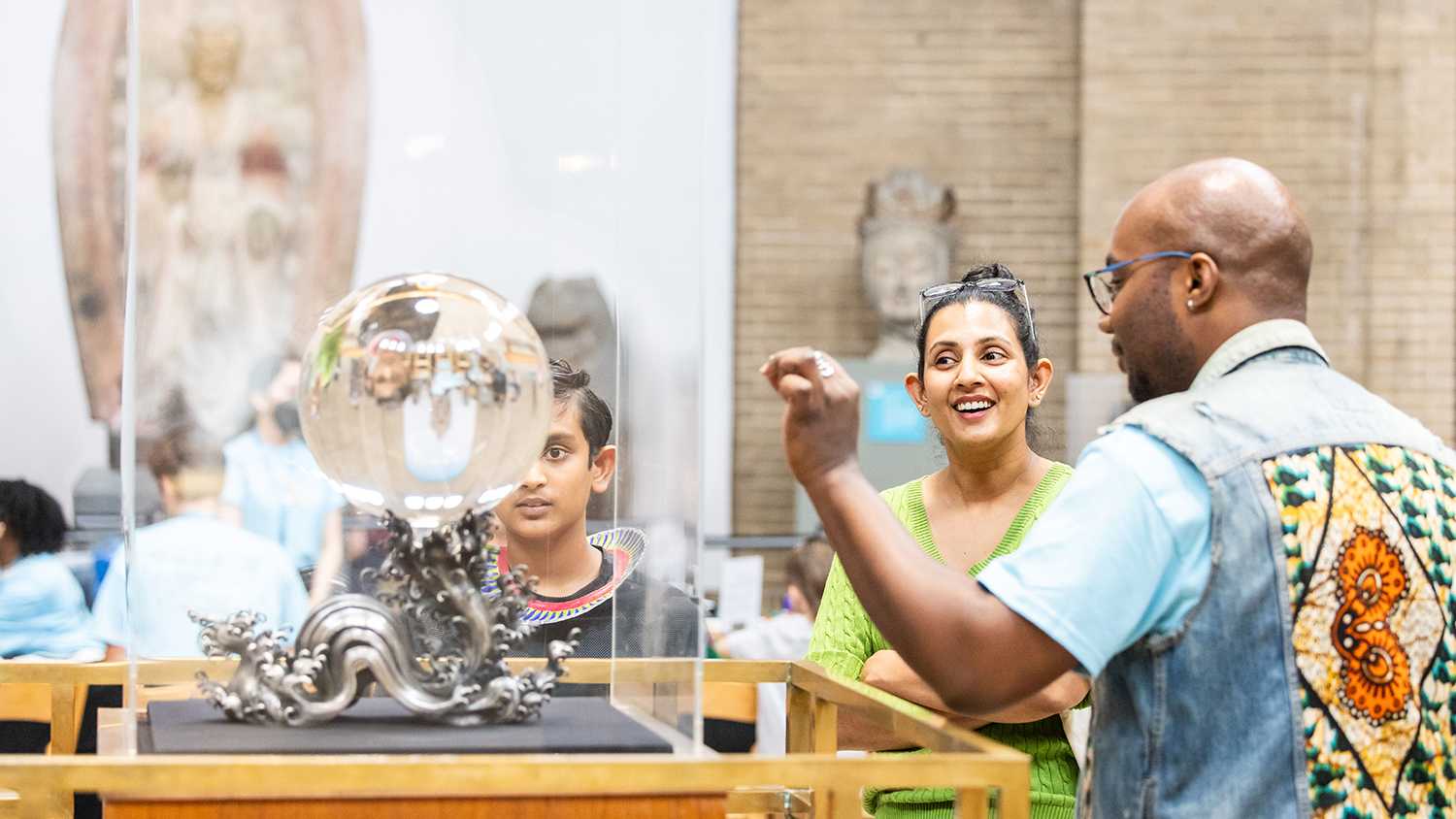 Museum visitors looking at a glass ball on display.