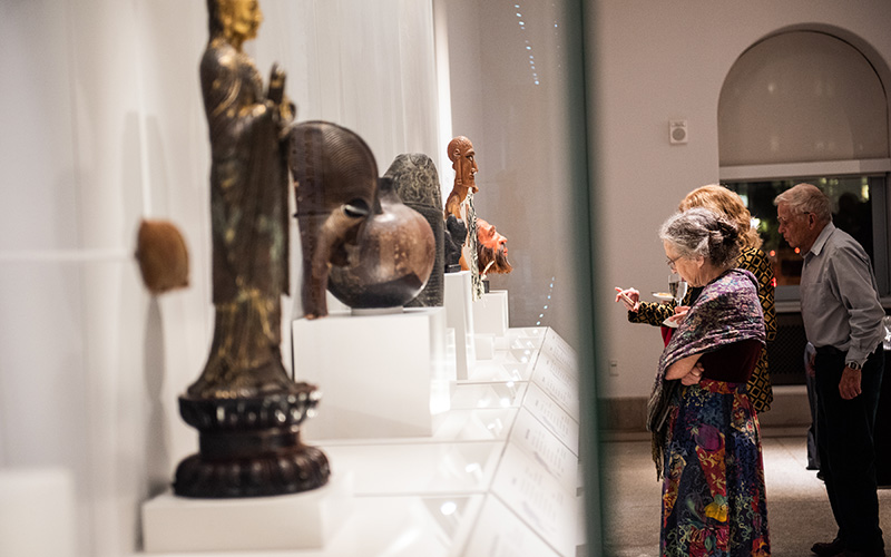 Three visitors looking at objects on display.