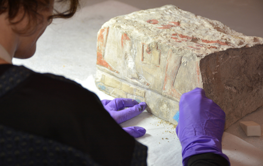 A conservator working with an Egyptian artifact.