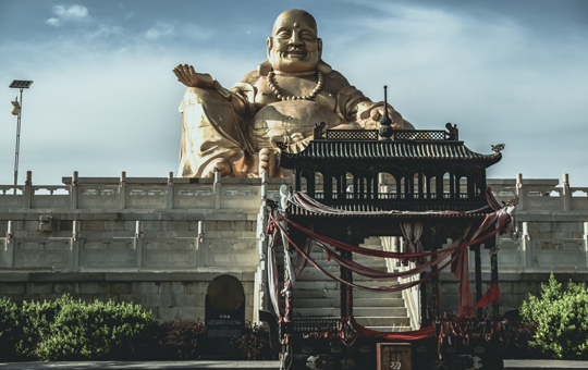 A monumental statue of the Buddha in the background of a Buddhist temple.