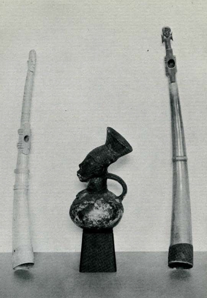 Two carved ivory trumpets and a pottery jug in the shape of a bust
