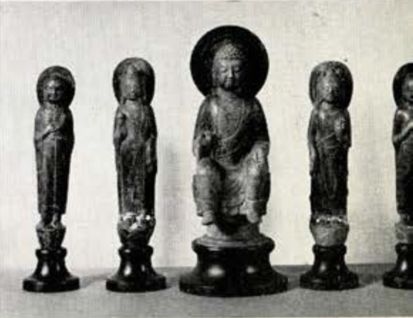 Four marble shrine figure of a bodhisattva, most likely Guanyin, with a jewelled headdress, necklace, and scarves, standing on a simplified lotus bud with oval halo, two on either side of a marble shrine figure of a seated Sakyamuni buddha on lotus throne with round halo