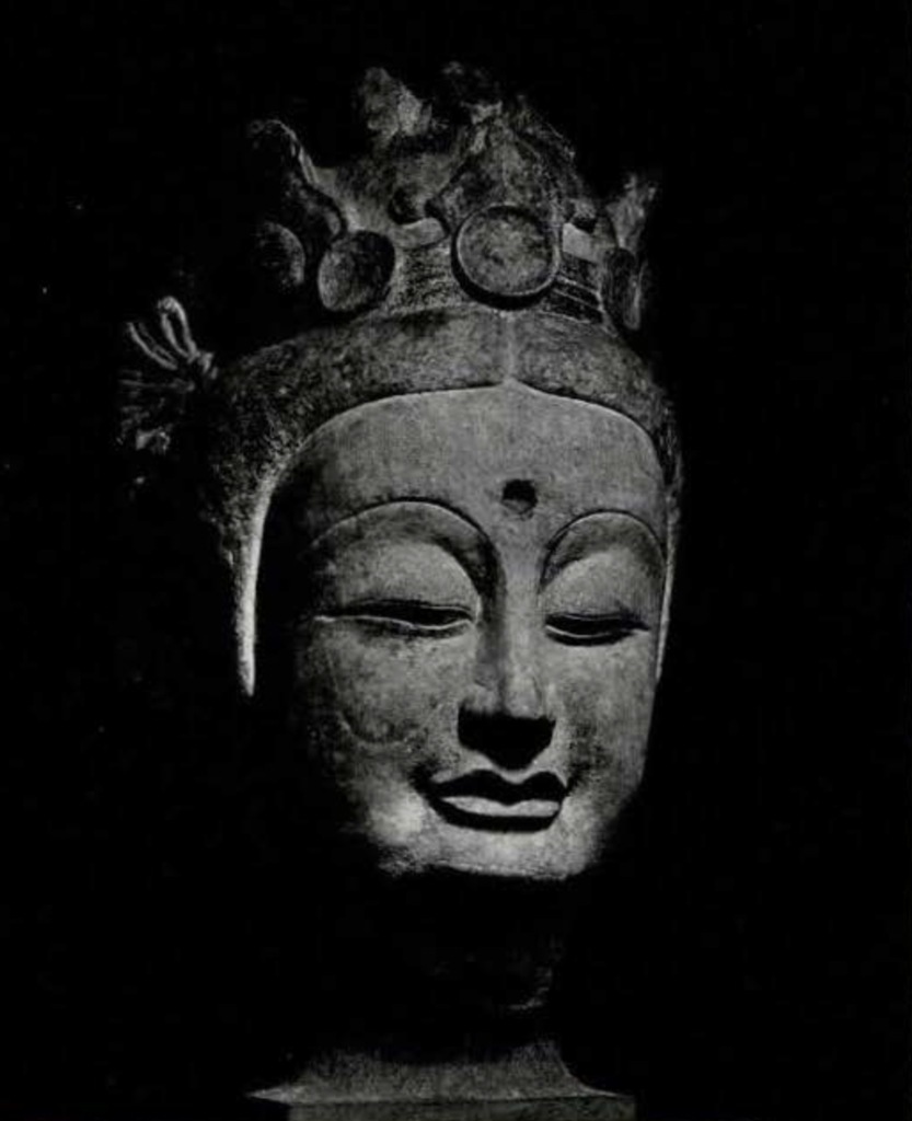 Colossal head of a bodhisattva statue, hair parted in the middle, three-peaked crown, and empty urna