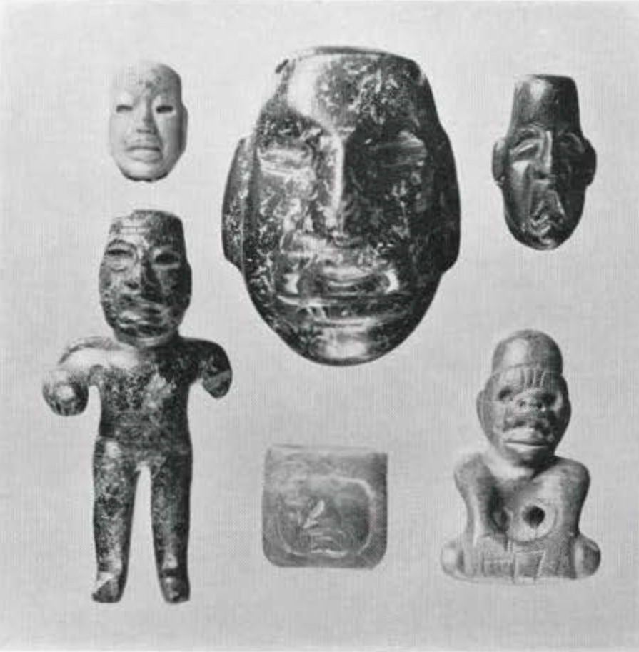 Small jadeite objects, several carved into the shape of faces, other into figures