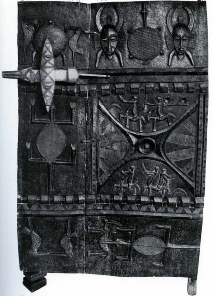 Carved and painted wooden door showing masks and warriors