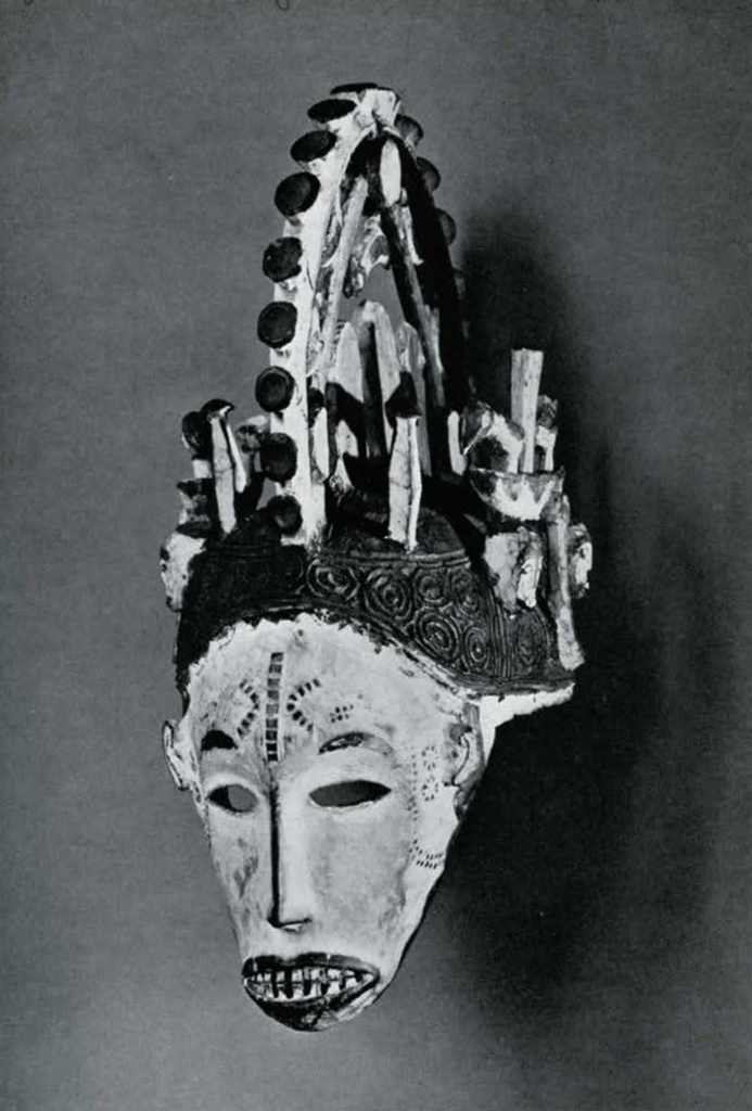 Wood mask with elaborate tall openwork crest above narrow whitened face