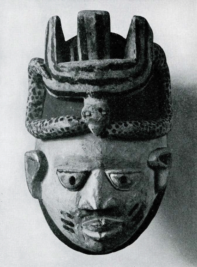 Wooden mask with a bird biting a snake above the face.