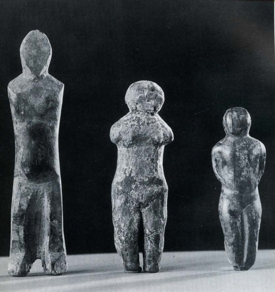 Three roughly carved dolls with no arms.
