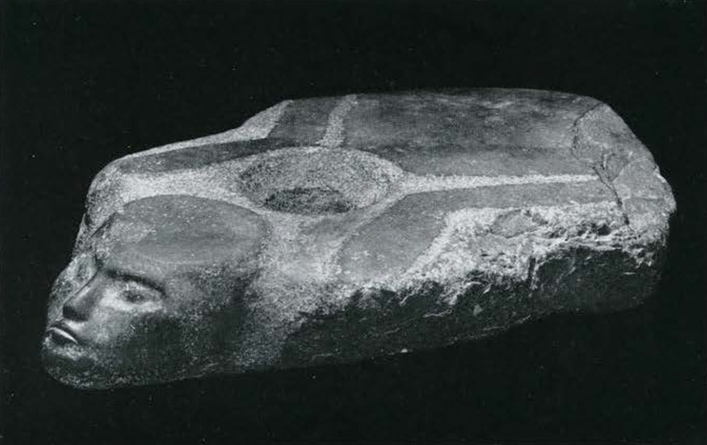 A stone temple door socket in the shape of a prisoner lying on his stomach with his arms bound behind him.