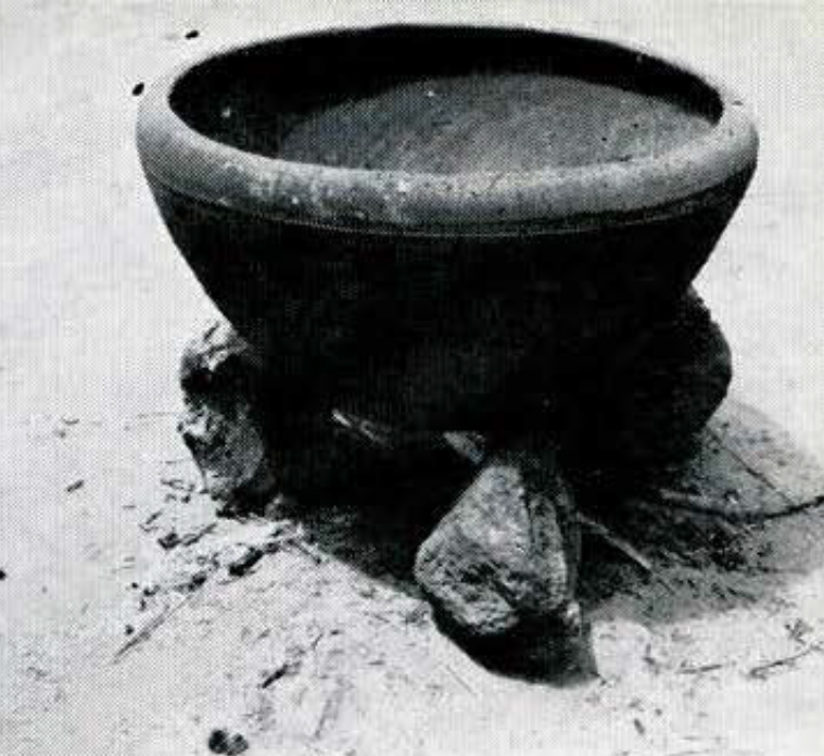 A round pot stitting atop some rocks.