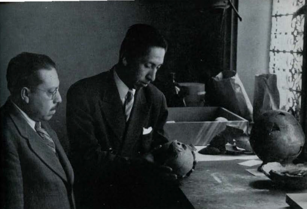 Two men examining a round pottery vessel.