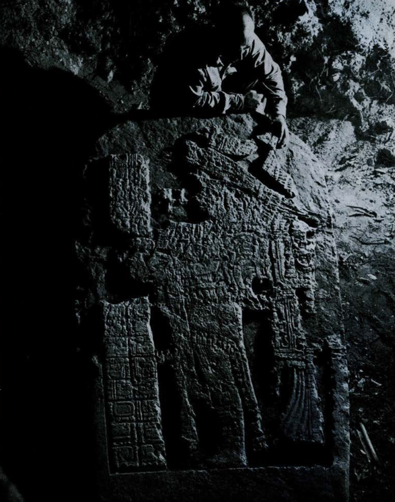 A man piecing together fragments back onto a large stone stela.