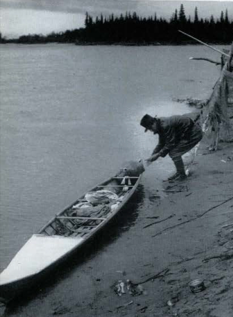 A man loading a kayak along the shore.