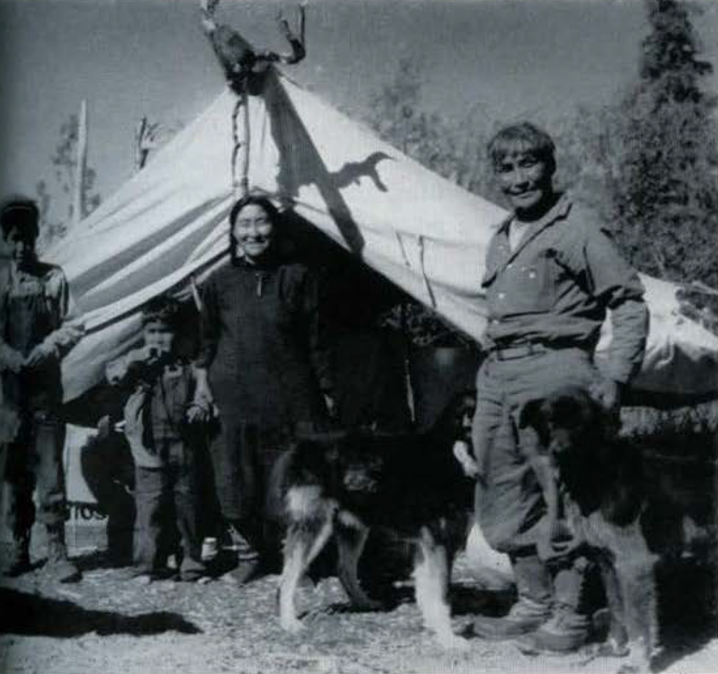 A family standing outside their tent, with dogs.