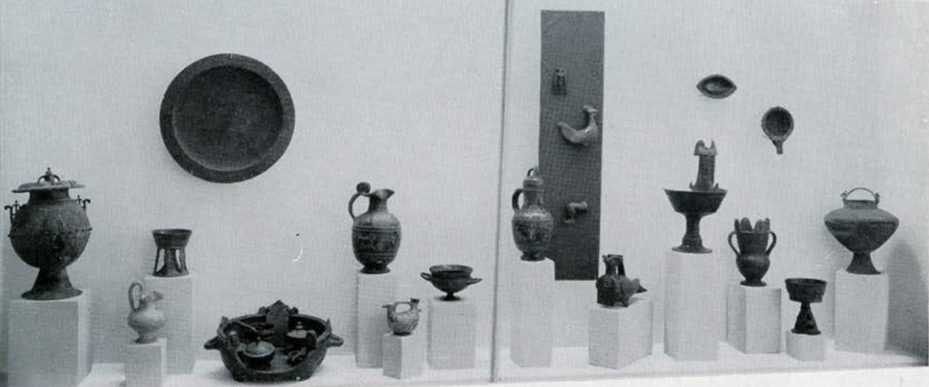 A variety of Etruscan objects on small pedestals in a glass case.