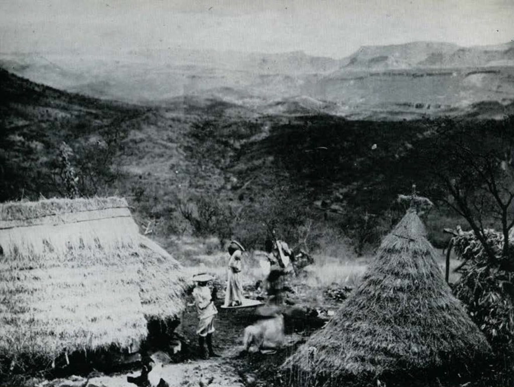 A family outside their houses amongst the mountains.