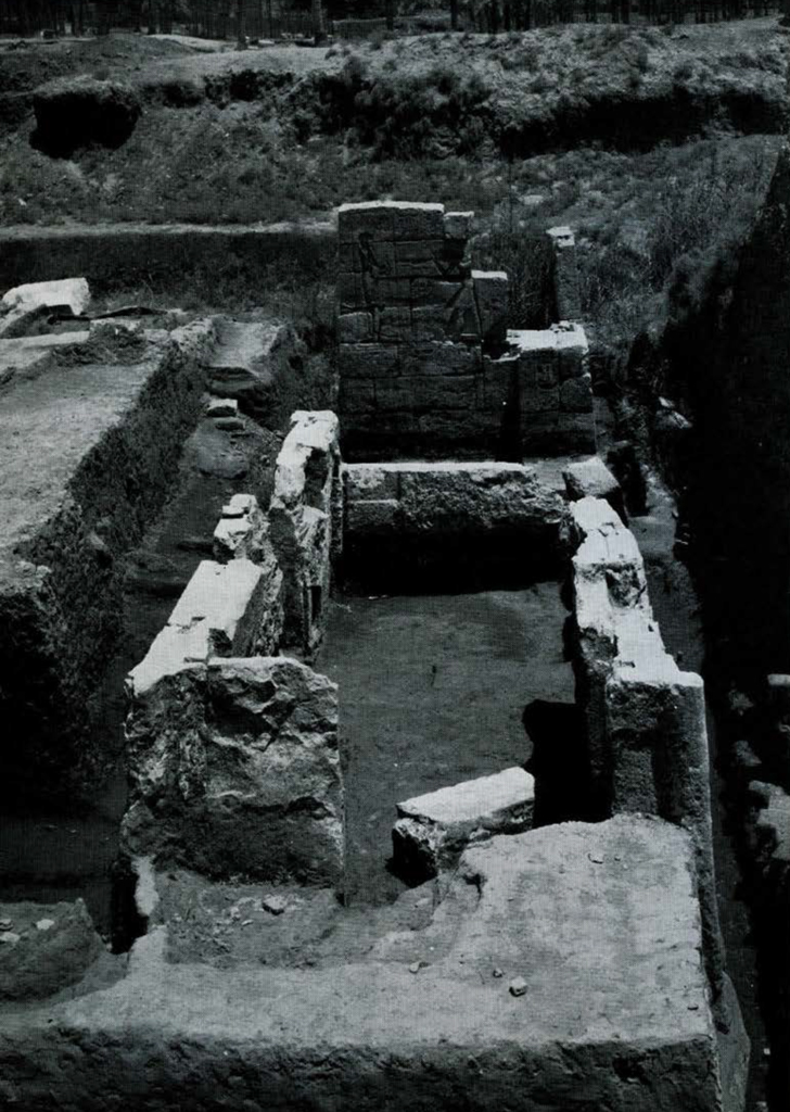 Excavated area of a building, a pylon with carvings in the center.