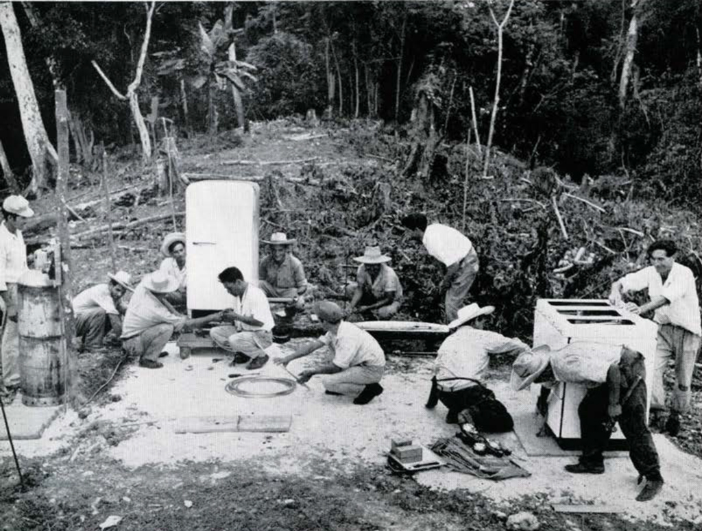 A group of people constructing a kitchen on the ground, in the middle of the jungle.