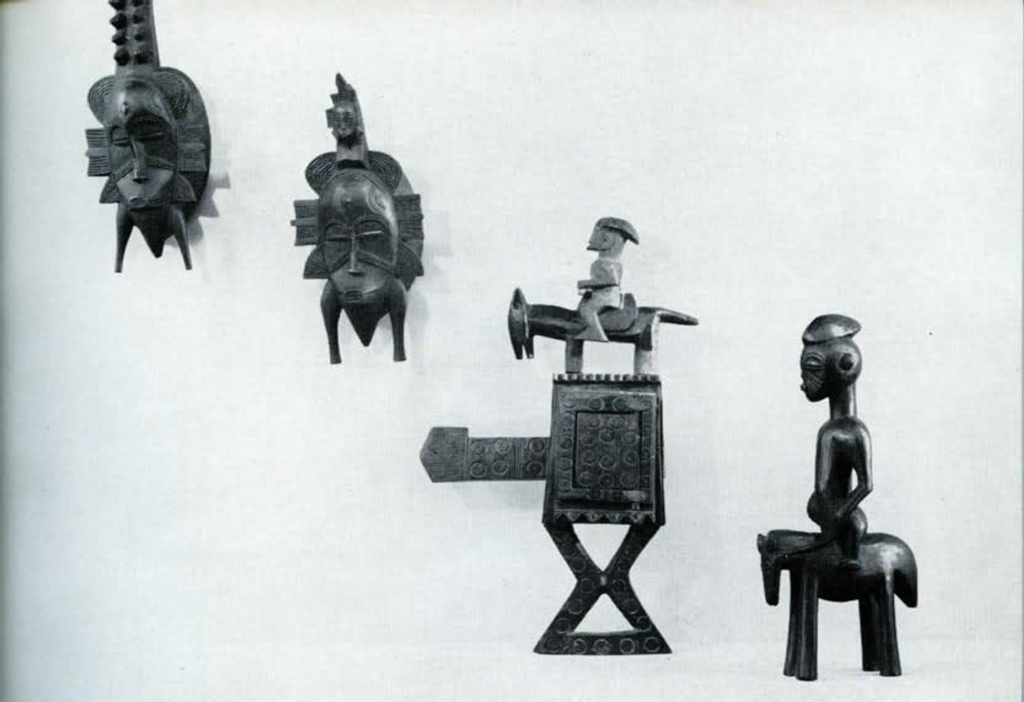 Two masks and two figures on horseback, mounted on a wall.