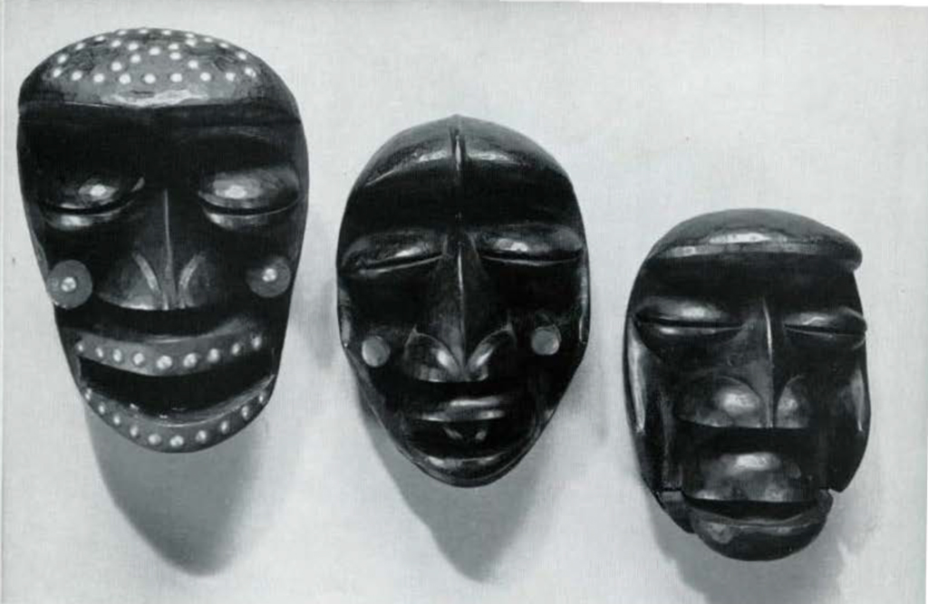 Three wooden masks with projected foreheads, bulging eyes with narrow slits, mounted on a wall.