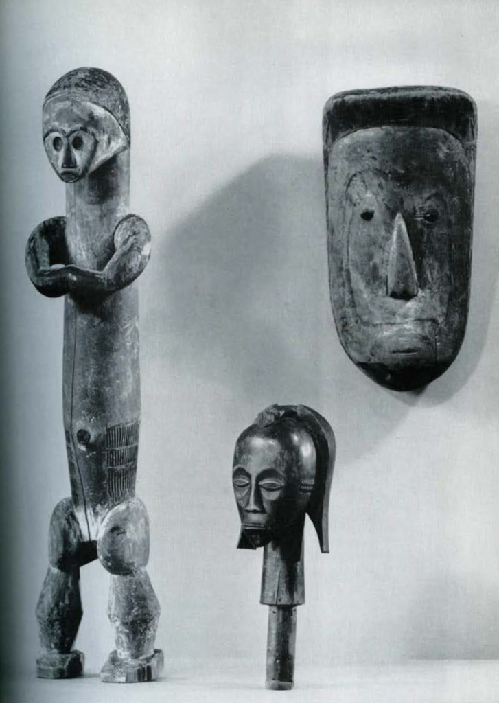 Carved wooden objects a figure with its armed cross, a head, and a mask.