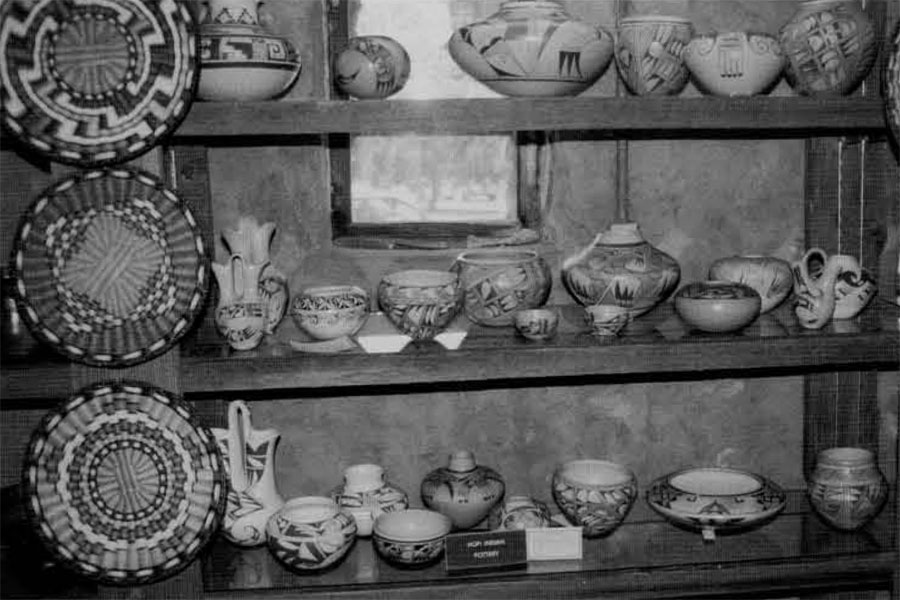 Three shelves of a variety of potteryware for sale.
