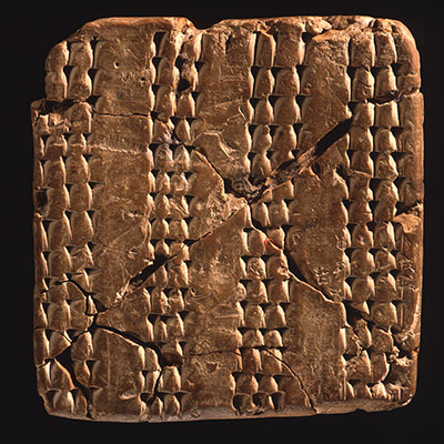A fragmented and pieced back together clay tablet covered in vertical wedge marks.