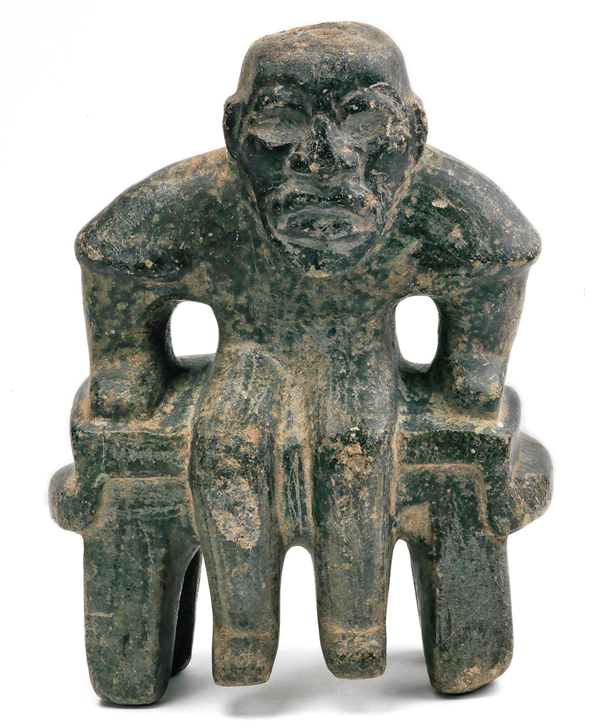 Stone carved human figure seated on bench (throne), arms to sides and hands resting on the bench