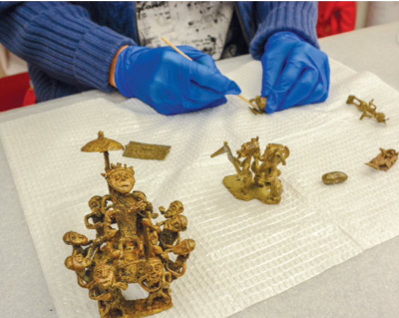 A conservator cleaning gold weights