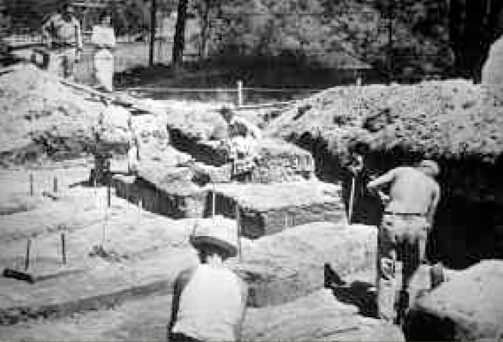 Two people excavating graves in the sun.