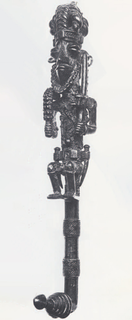 Staff with handle of a seated man holding a sword, a tusk on both hips.