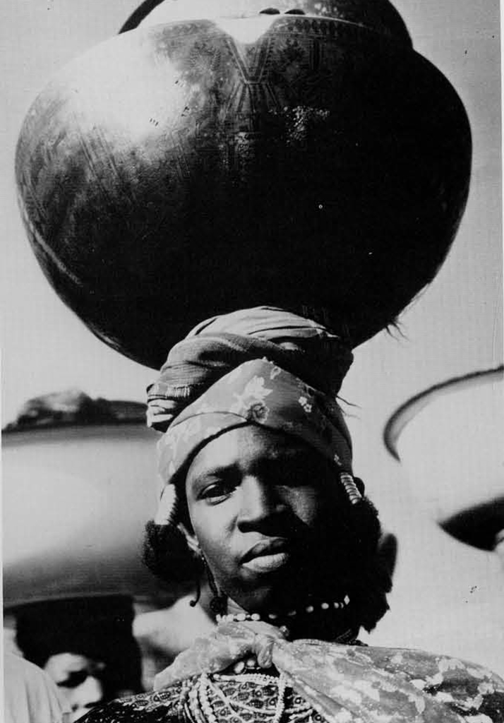 A woman balacning a massive calabash on her head.