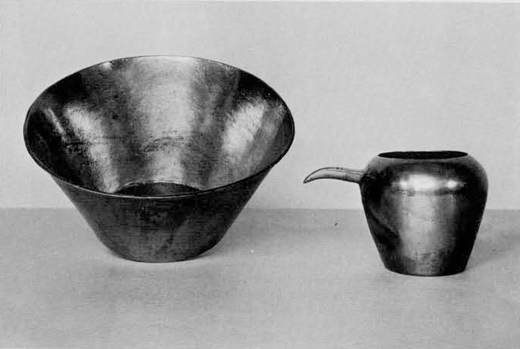 A metal bowl with a flat bottom, and a smaller ewer.