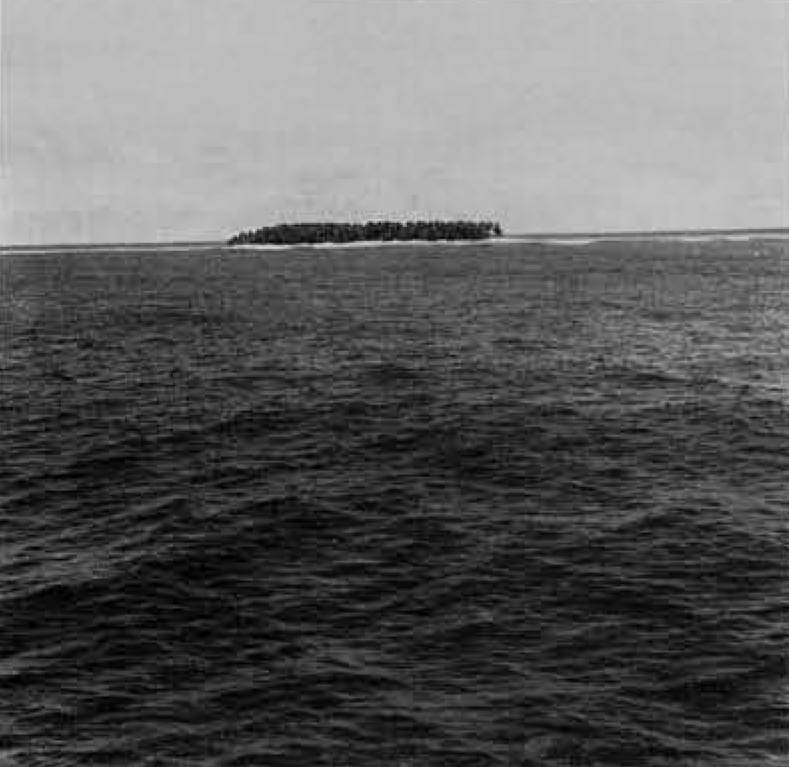 A small island in the ocean, seen from a distance.