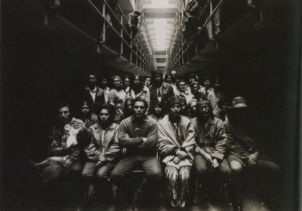 A group of protesters seated and standing in an Alcatraz Island cell in protest.