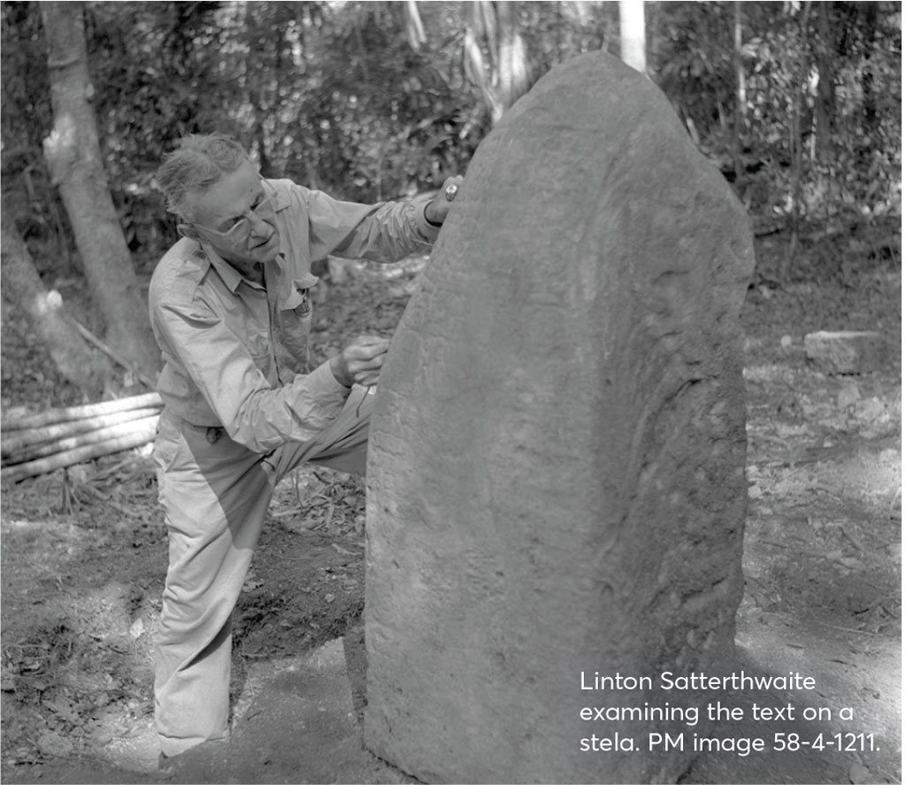 A man closely examing a large stone stela.