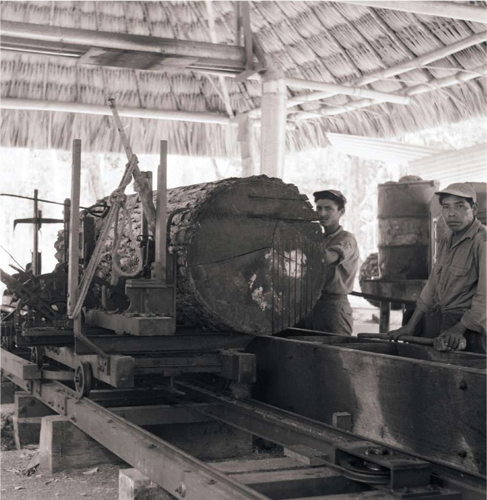 Two people standing next to a sawmill.
