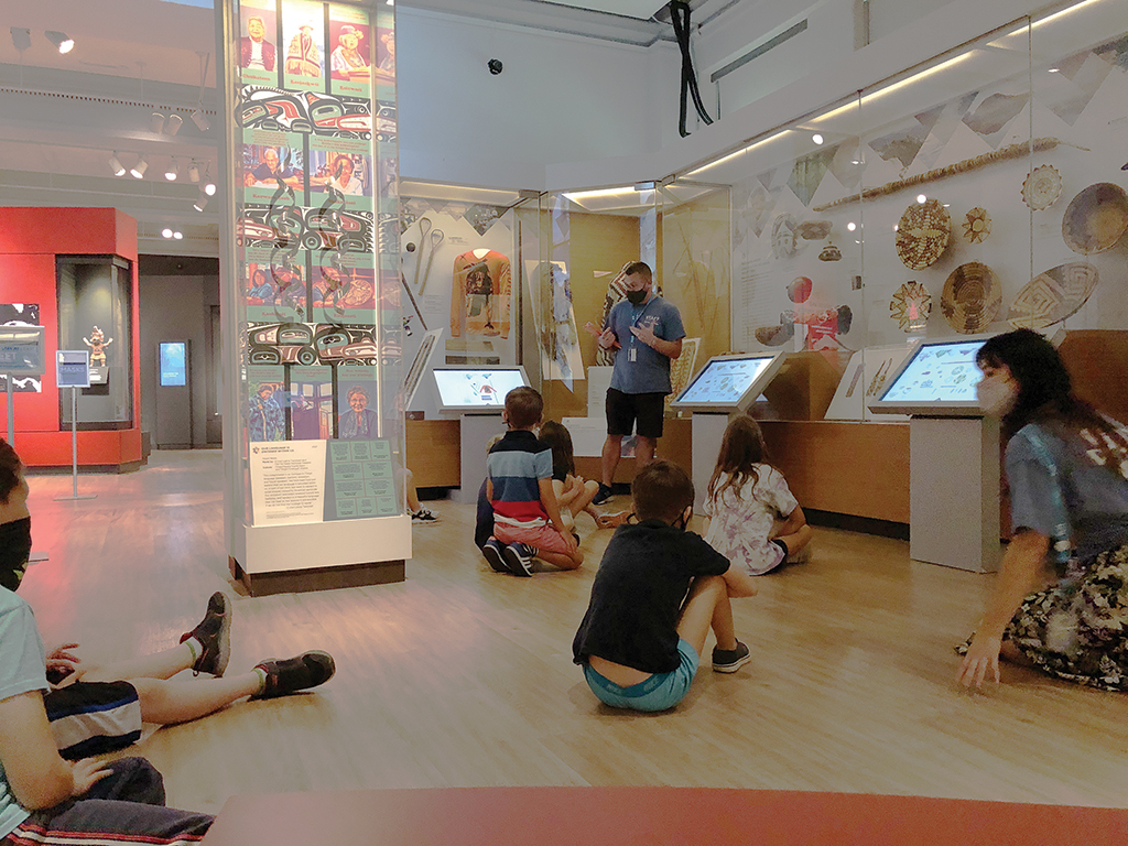 Students sitting in a gallery with two museum staff members
