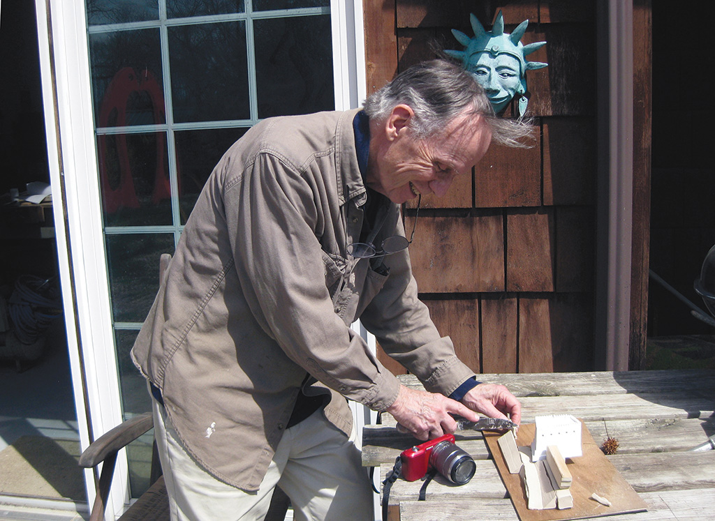 Man working with small pieces of wood outside home.